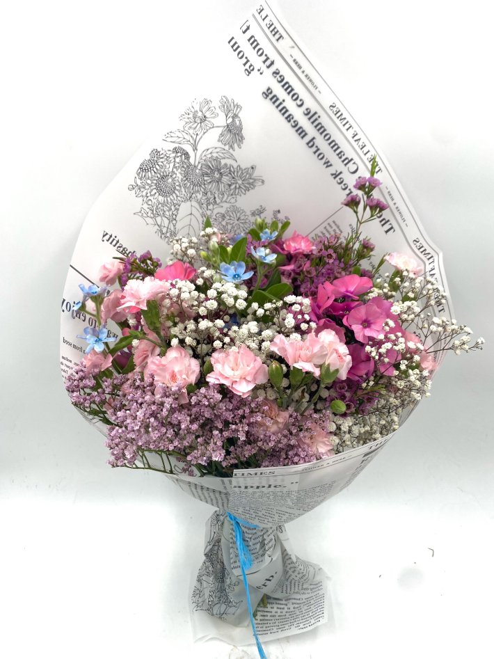 זר פרחים צבעוני עם פרחים ורודים, סגולים, לבנים וכחולים, עטוף בנייר מעוצב בסגנון עיתון וקשור בסרט כחול.